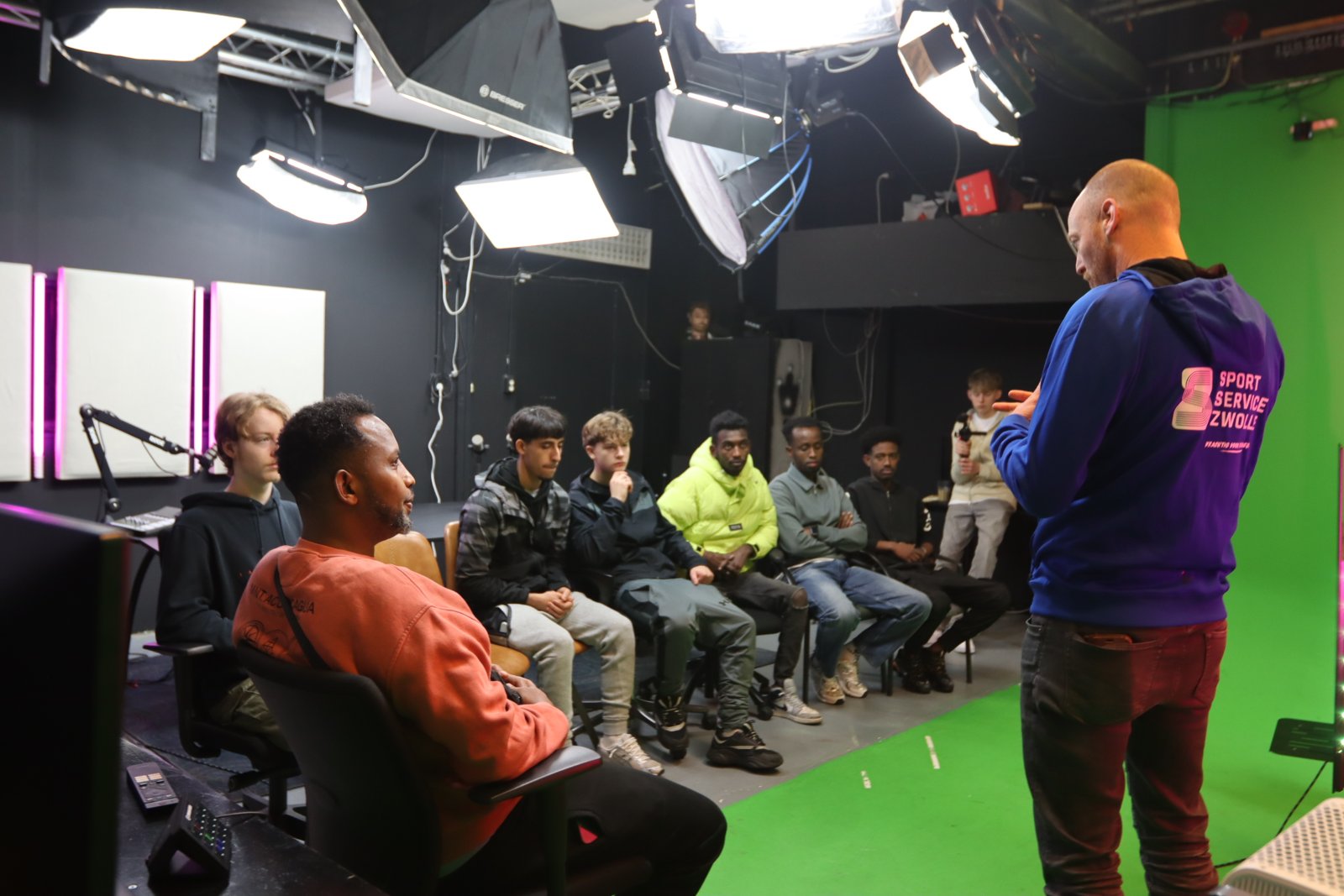 Een coach spreekt een groep jongeren toe in de studio